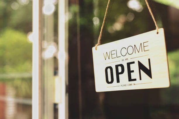 A business sign that says " welcome we are open " in the door