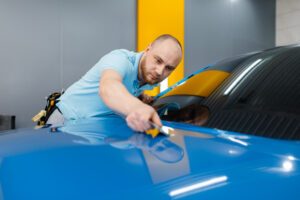 worker installing a customized color blue wrap into the vehicle.