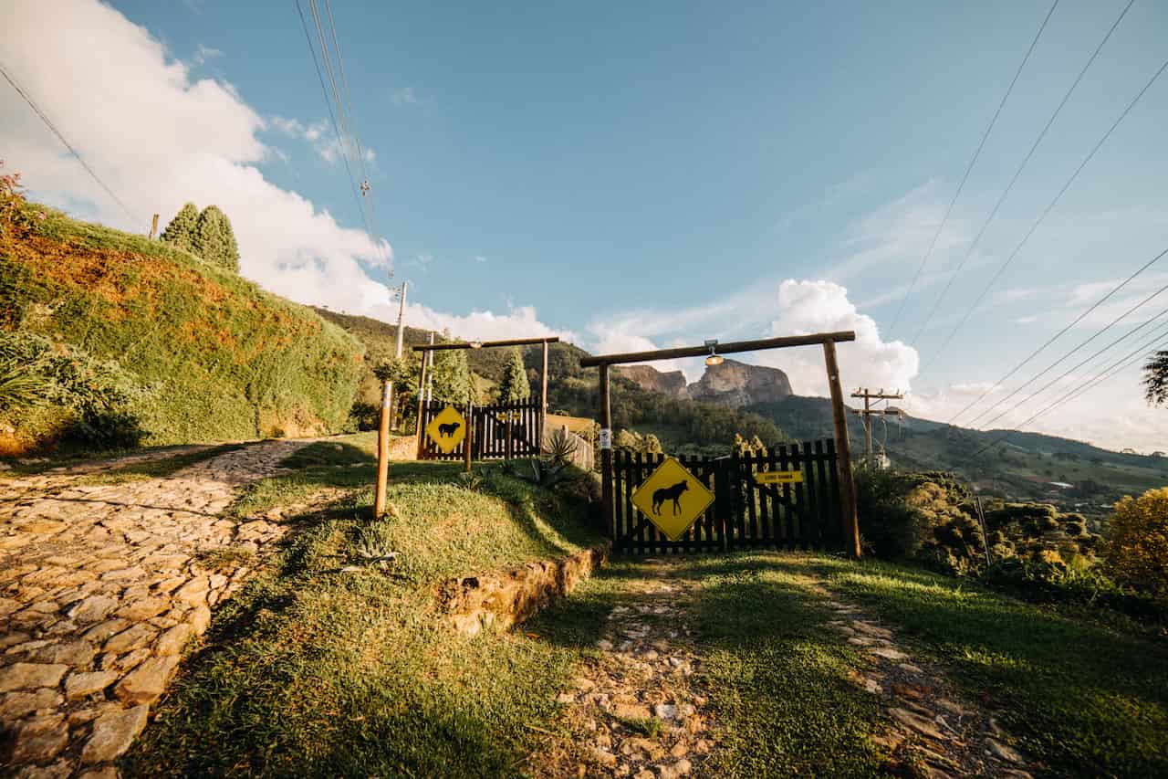 Scenic view of a rustic gate along a rural road with mountains in the background.