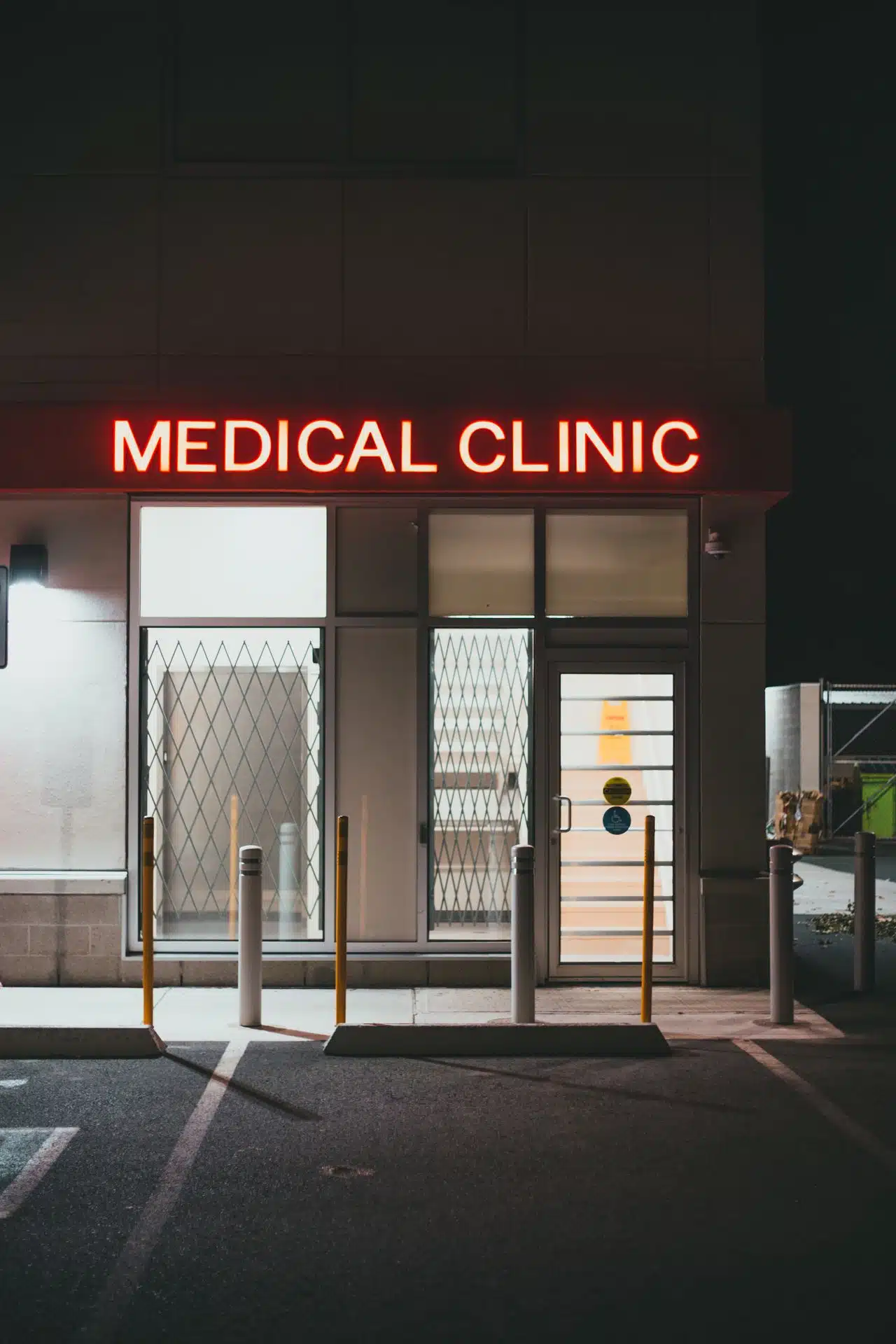A vertical night shot of a medical clinic storefront featuring a bright red illuminated channel letter sign.