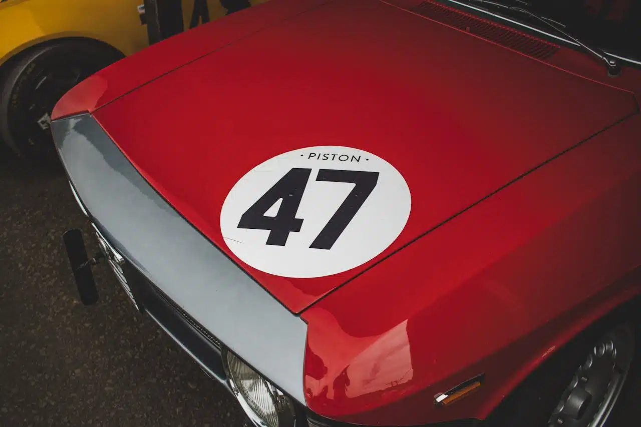 Custom vinyl vehicle graphics showing a white racing roundel decal on a red classic car hood.